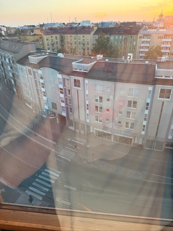 Auringonlasku Kallion kattojen yllä, kuvattu Kurvin ikkunasta