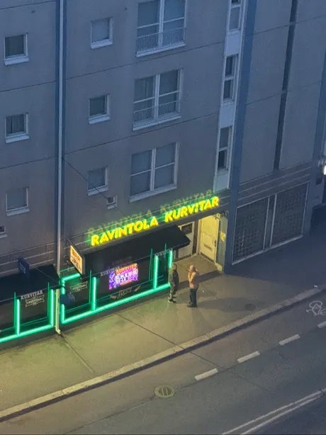 Ravintola Kurvitarin neonkyltit yöllä, kuvattu ylhäältä samasta ikkunasta