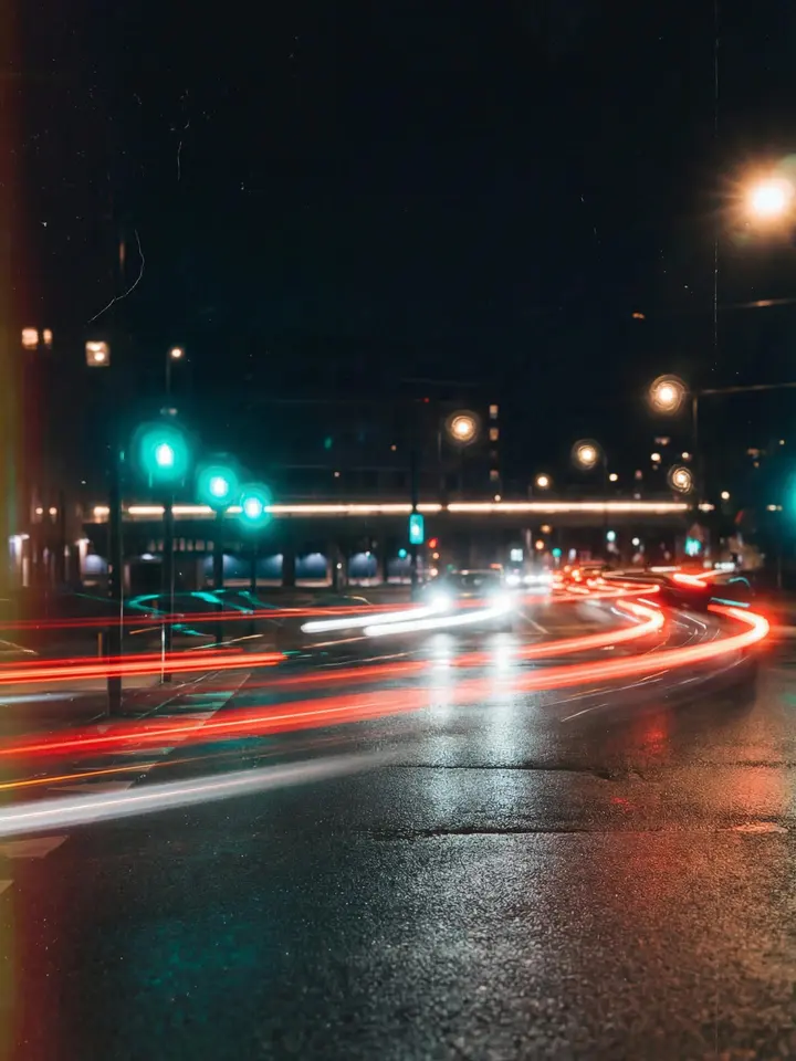Autojen punaisia ja valkoisia valojuovia märällä kadulla